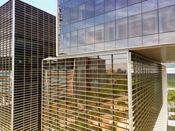 istock Bottom view of office building window close up, reflection and perspective. Modern architecture with sun ray. Glass facade on a bright sunny day with sunbeams on the blue sky. 1776508911