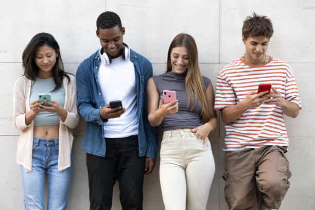 istock Diverse group of young people texting leaning against a wall. Happy group of friends using their phones in the street. 1776528340