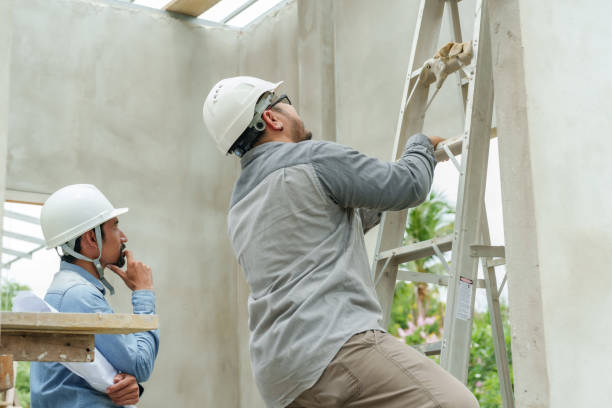 istock Multiethnic employees construction workers, engineers wearing safety helmets Climbing the ladder check dryness cement applied wall. architect standing intently looking mistakes walls  work structure. 1776530499
