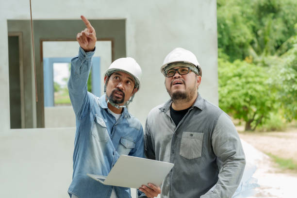 istock Architectural manager employee engineer foreman Asian male Standing holding laptop pointing building Look at  problems building house projects Wear white safety helmet protect yourself falling objects 1776530553