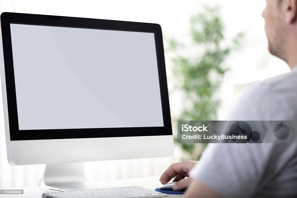 young man working on computer Rear view of a young man working of a computer Adult Stock Photo