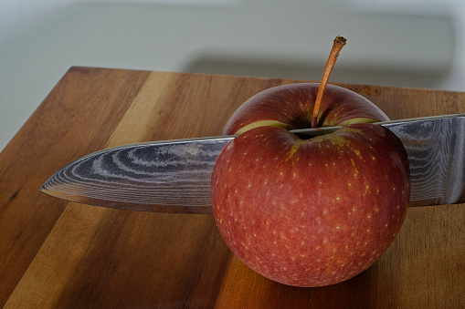 Red Apple on a plate and a tape measure rolled up a fork on light blue background.\nDiet concepts.