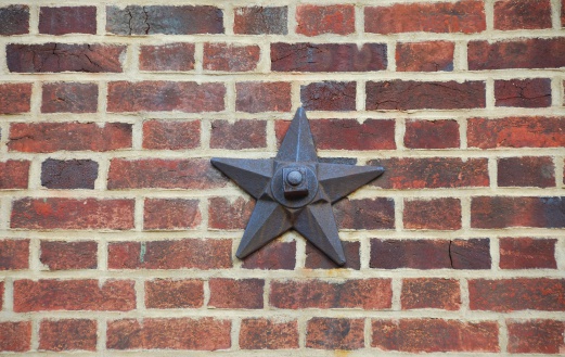 Photograph of an antique metal barn star on a brick wall. Barn star's are found throughout the State of Pennsylvania and are thought to bring good luck.