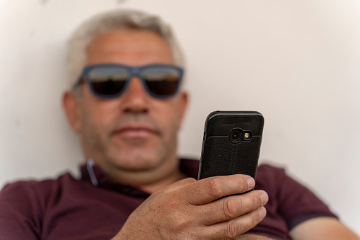 Old man using a smartphone. Old man using social media.
