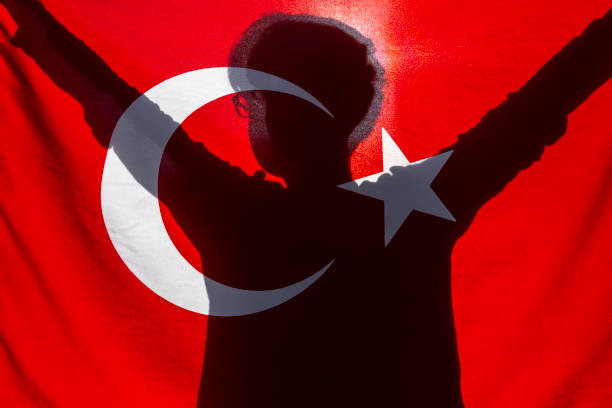 Boy silhouette behind Turkish flag at sunset