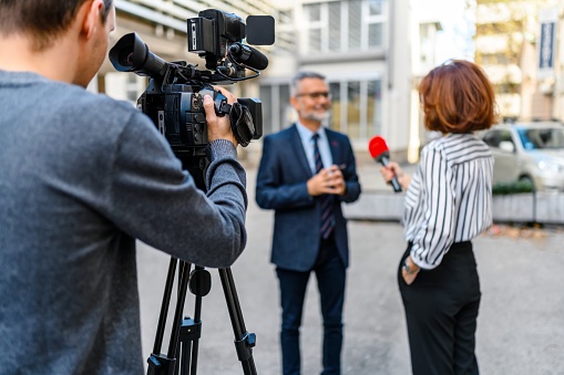 A female journalist with a microphone interviewing a businessman