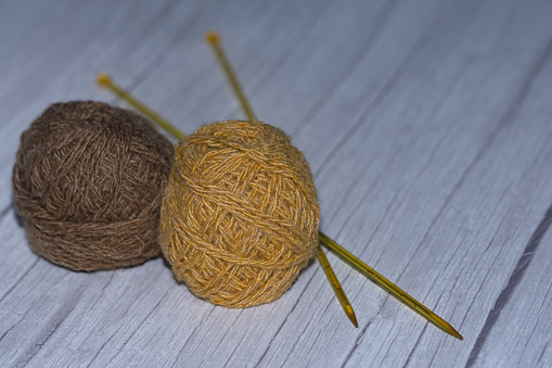 Balls of yarn and plastic knitting needles on a white wooden background.