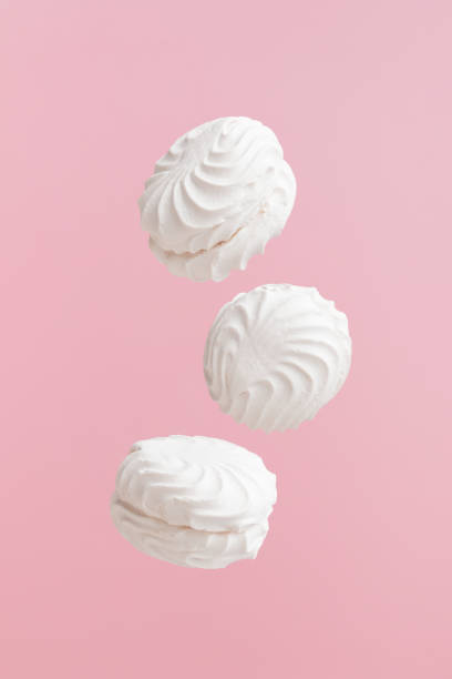 istock Three soaring white zephyr marshmallow on pink background. flying food levitation 1776658445
