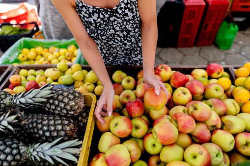 Cropped shot of woman's hand buying fresh apples from fruit shop in market