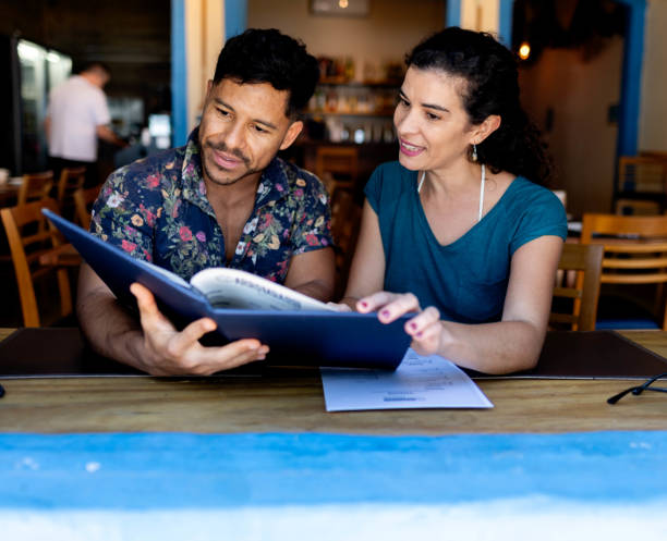 istock Happy young couple at restaurant looking at menu card 1776666772