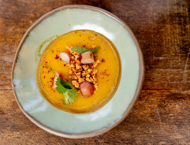 Table top view of roasted autumn butternut squash bisque served in a plate on wooden table