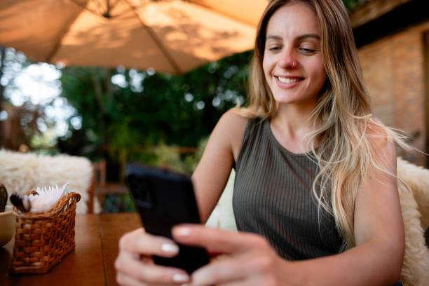 istock Pretty young woman using mobile phone sitting at outdoor cafe table 1776667393