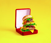 Large burger in red velvet gift box on yellow background. Minimal art creative collage.
