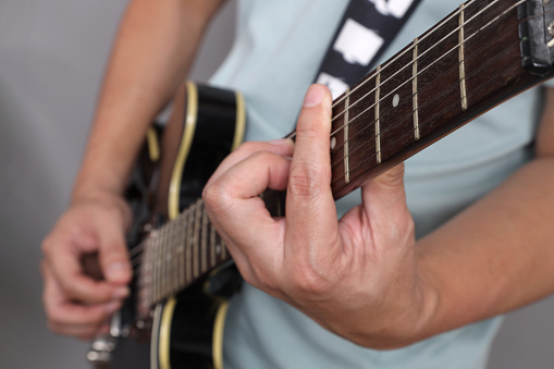 The close up of an asian man holding of a guitar while performing