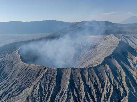 Aerial landscape view of the Bromo volcano crater with smoke coming. An active volcano in Tengger Semeru National Park in East Java, Indonesia.