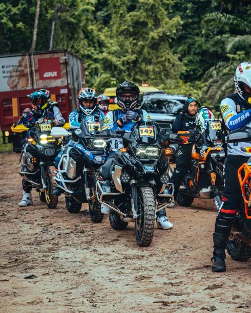 a line of motorcyclists are lined up in the dirt Pahang, Malaysia – September 22, 2022: A group of motorcyclists are gathered in a dusty area, lined up in a formation, ready to take off Revving stock pictures, royalty-free photos & images