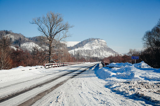 tire tracks in the snow, winter road, empty road in winter goes far to the horizon, covered with snow path, winter landscape