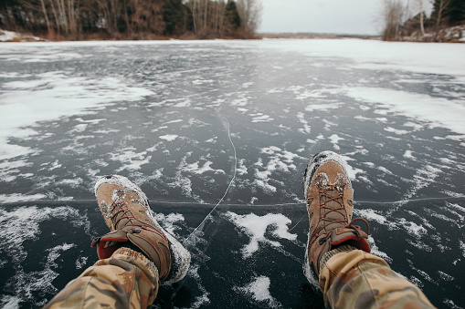 feet on ice, a man sitting on the ice of a lake, bubbles in the ice, winter outside the city, nature, recreation