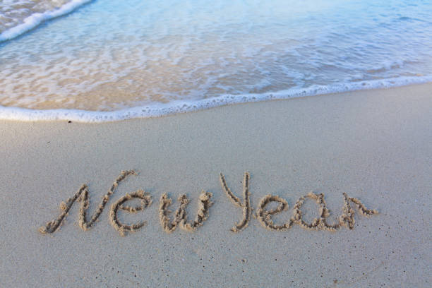 2022 Happy New Year inscription sand beach. The written text is written on yellow sand and is washed away by a wave. The concept of changing the year, the holiday. Mockup postcards copy space