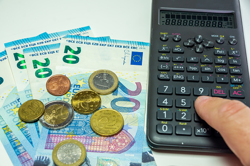 Monetary Calculations: Finger Typing on a Calculator among Euro Bills and Coins.