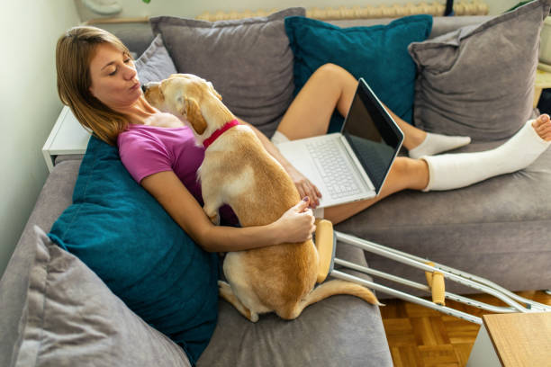 istock Woman with cast on her leg playing with dog 1776794903