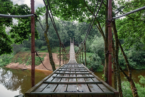 Hanging monkey bridge over the Minija river in Lithuania. Shot from a low angle straight from the front.