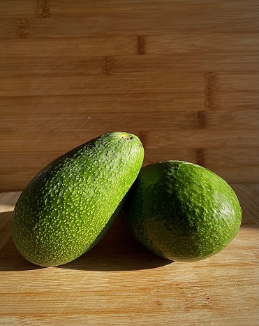 Two ripe limes cut in half and placed on a wooden cutting board, ready to be used for cooking or garnishing