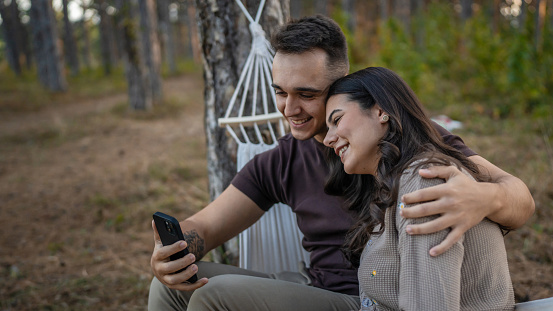 Man and woman young adult couple in nature take self portrait photo selfie ugc use mobile phone smartphone or make a video call