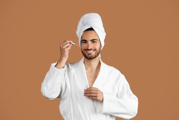 istock Middle Eastern Guy Applying Facial Serum Moisturizing Skin, Brown Background 1776806217