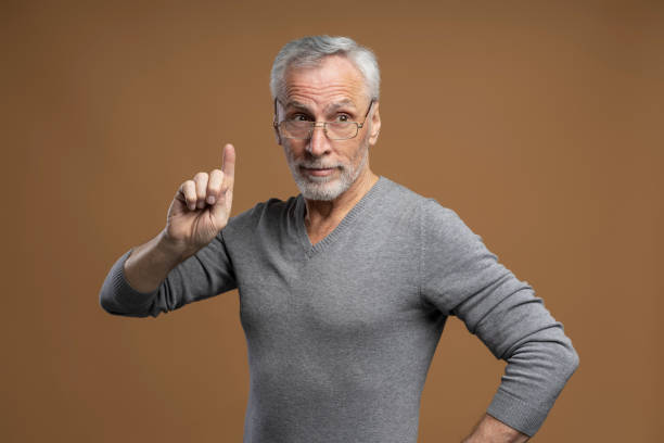 istock Serious gray haired senior retired man in eyeglasses, points finger up, thoughtfully looking aside 1776812426