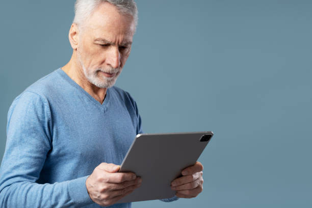 istock Senior man holding digital tablet communication online isolated on blue background. Technology 1776813514