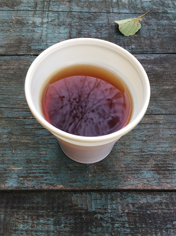 High angle view a plastic cup of Turkish tea on outdoor wooden table