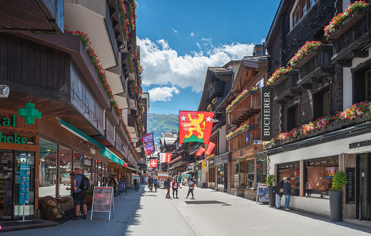 Zermatt, Switzerland - July 6, 2022: Bahnhofstrasse is a popular main street filled with stores and leads to the central Zermatt train station.