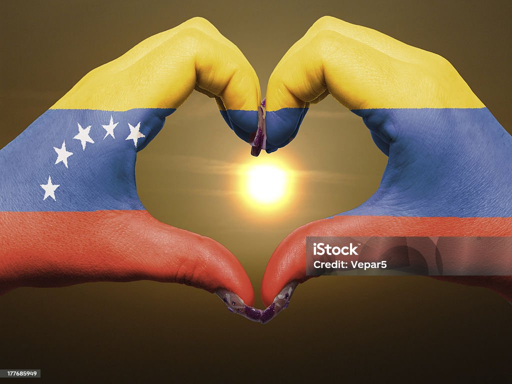 Heart and love gesture by hands colored in venezuela flag Tourist gesture made by venezuela flag colored hands showing symbol of heart and love during sunrise Colors Stock Photo
