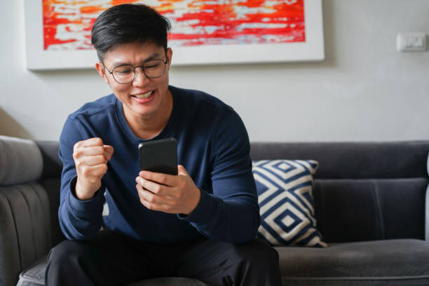 istock close up young asian man use smartphone and raised hand with excited feeling after checking challenge game on website for technology and leisure concept 1776880181