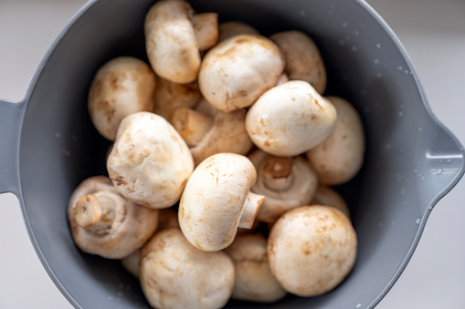 Washed white raw mushrooms in bowl