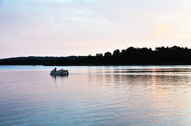 Boat after Sunset Pontoon boat on the lake just after sunset. pontoon boat stock pictures, royalty-free photos & images