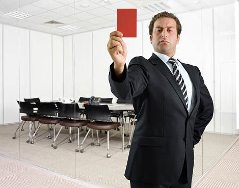 Businessman showing red card in an office meeting room