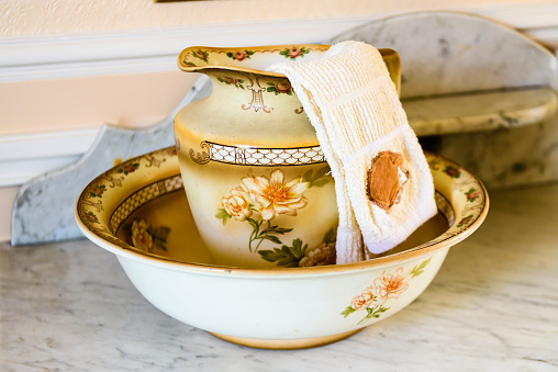 Old fashioned ceramic washbowl and jug with a facecloth.