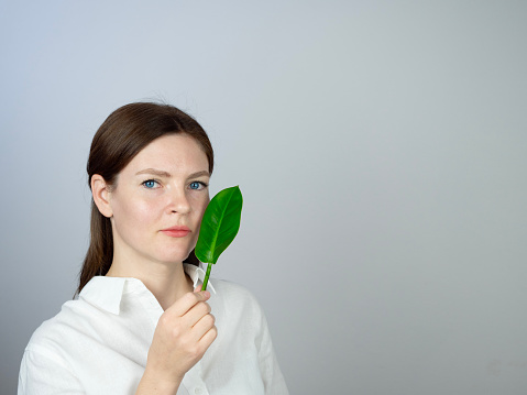 Portrait of Woman holds a leaf on white background, environment and environmental sustainability concept photography with copy space