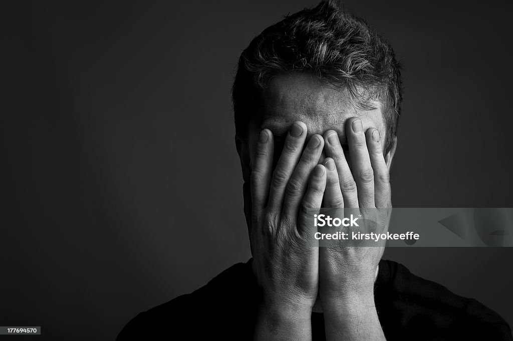 Despair Black and white portrait of a man with his head held in his hands. Copy space to the left. Men Stock Photo