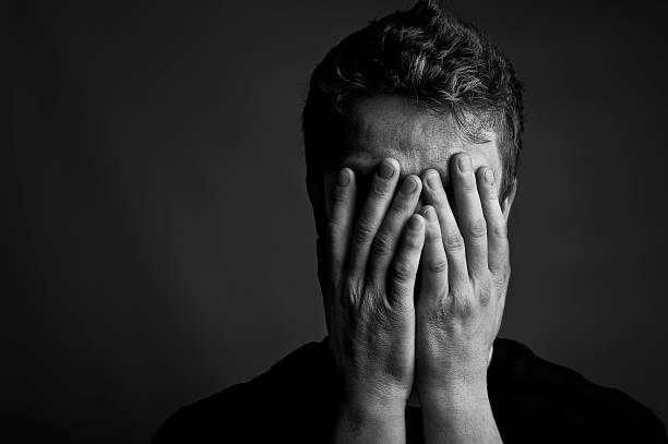 Despair Black and white portrait of a man with his head held in his hands. Copy space to the left. man crying stock pictures, royalty-free photos & images