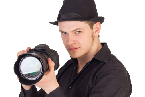 Closup portrait of young man photographer taking a photo with camera isolated on white background
