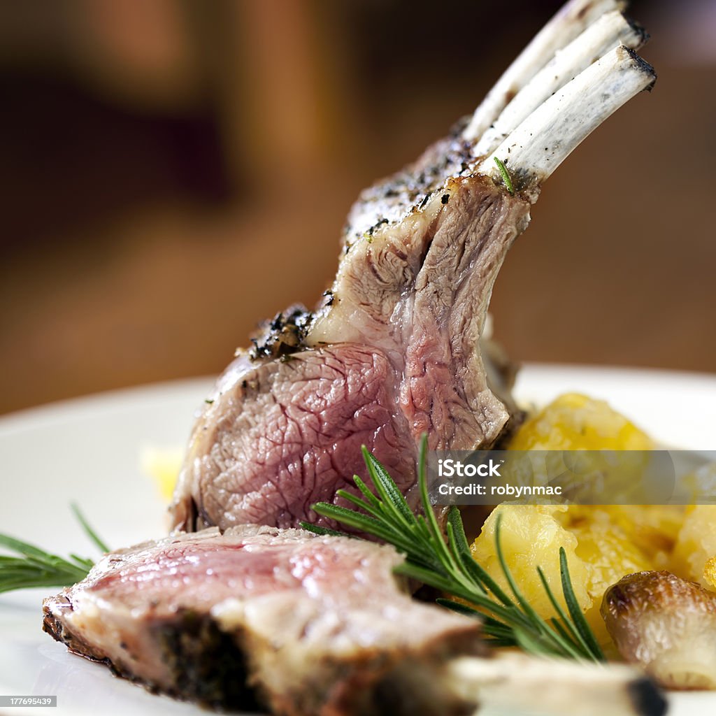 Medium rare rack of lamb next to squash Rack of lamb with rosemary and roasted potatoes. Rack of Lamb Stock Photo