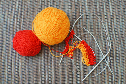 High angle view of balls of knitting thread, knitting needles and reading glasses.