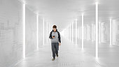 Japanese casual young man walking and text messaging in futuristic corridor