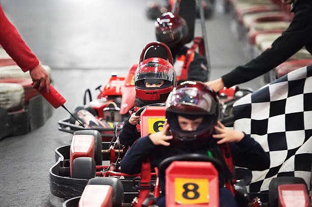 Row of children in go-karts with helmets ready for a race Competition for children karting indoors go carting stock pictures, royalty-free photos & images