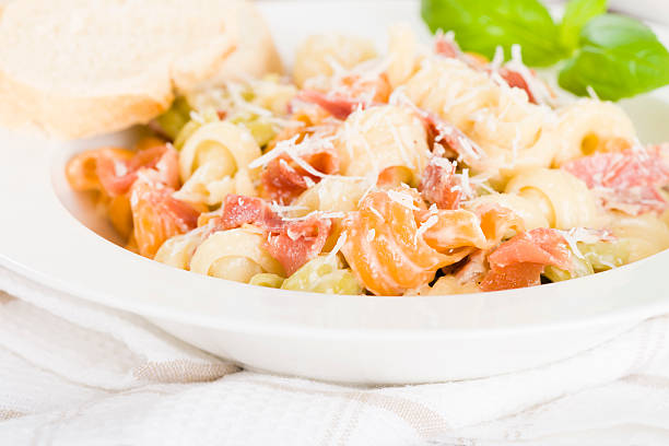 Italian tricolour pasta with creamy sauce and parma ham garnished with parmigiano reggiano. Crusty bread on side.