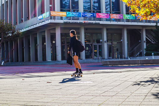 Berkeley, CA, USA - November 11, 2022. Teenage girl skateboarding in UC Berkeley campus.