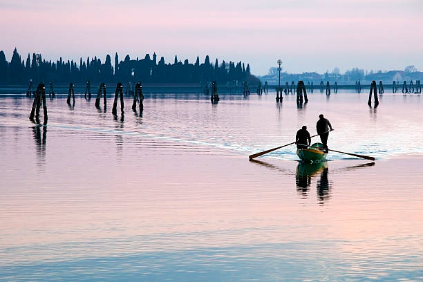 Venice sunset silhouette of men rowing   in the lagoon